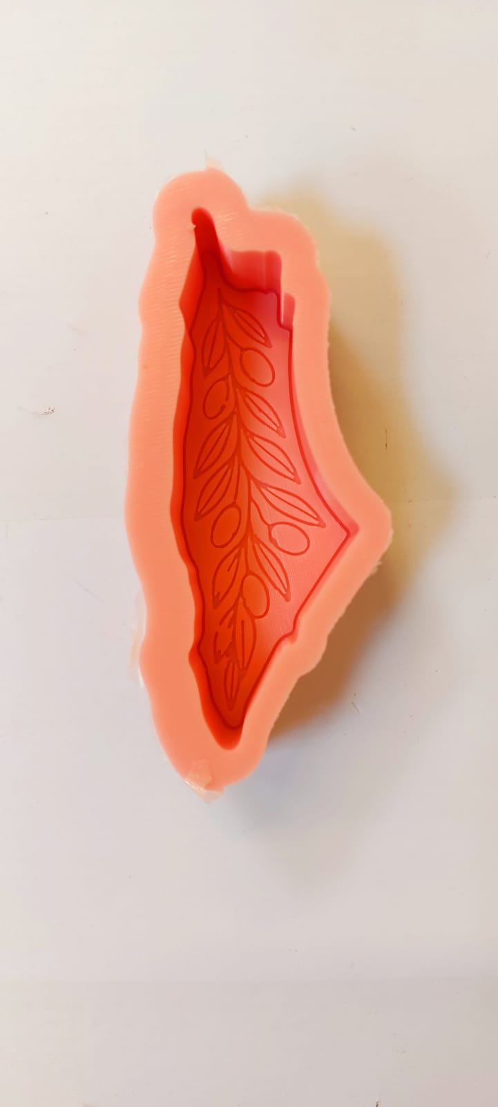 A distinctive, flexible silicone mold shaped like the map of Palestine and adorned with olive branch motifs; precision