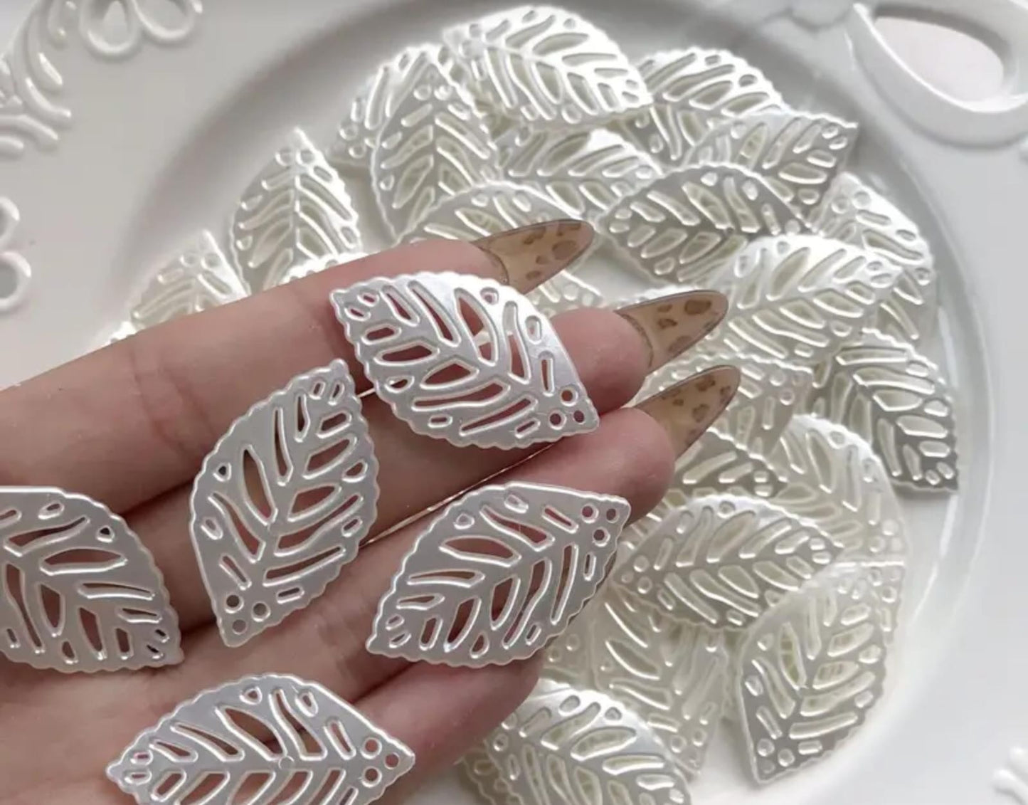 These hollow, leaf-shaped pearl fillers and embellishments are very delicate and popular in crafts. They are used inside clear resin molds or glued onto the surfaces of incense burners, trays, and jewelry boxes to give them an elegant and subtle touch