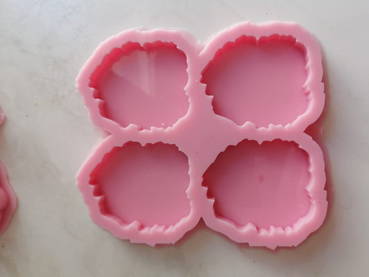 A silicone mold with four nearly circular cavities, but featuring irregular, wavy edges, used to make artistic keychains, pendants, or even small pieces to decorate wall art or create decorative pieces resembling gemstones