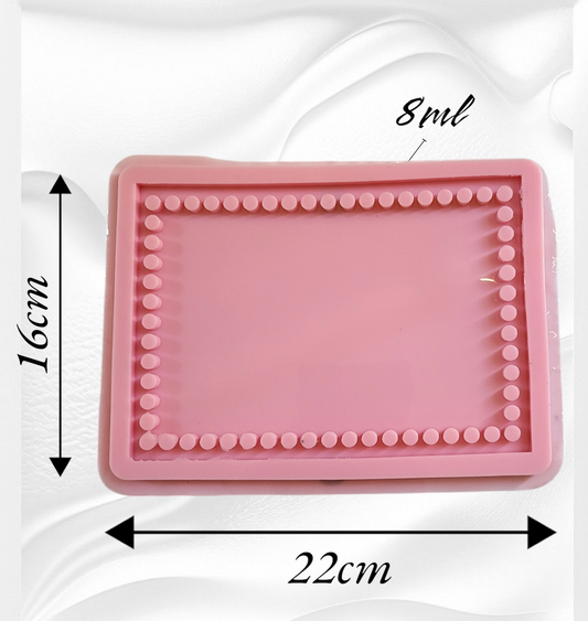 A light pink silicone mold featuring a unique design with an inner frame of small raised circles surrounding the flat area in the center. Length: 22 cm, Width: 16 cm, Depth: 8 mm
